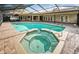 Aerial view of the pool and spa, surrounded by a brick-paved patio and screened lanai at 2392 Hillcreek E Cir, Clearwater, FL 33759