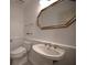 Half bath features white wainscoting, pedestal sink, and a decorative gold-framed mirror at 2392 Hillcreek E Cir, Clearwater, FL 33759