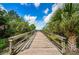 Straight-on shot of a wooden pier lined with sturdy wooden railings extending into green foliage at 2392 Hillcreek E Cir, Clearwater, FL 33759