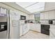 Well-lit kitchen with white appliances, white cabinets, tile flooring, and stainless steel refrigerator at 2427 Twin Dr # 2, Sarasota, FL 34234