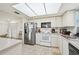 Well-lit kitchen with white appliances, white cabinets, tile flooring, and stainless steel refrigerator at 2427 Twin Dr # 2, Sarasota, FL 34234