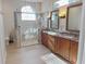 Bathroom with dual sink vanity, a tiled shower, and a large arched window for natural light at 2679 Saddlewood Ln, Palm Harbor, FL 34685