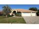 Charming single-story home featuring a tile roof, arched entryway, well-manicured lawn, and three-car garage at 2679 Saddlewood Ln, Palm Harbor, FL 34685