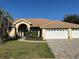 Charming home with a tile roof, arched entry, columns, and a well-manicured lawn at 2679 Saddlewood Ln, Palm Harbor, FL 34685