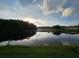 Picturesque pond reflecting the sky with green shoreline and homes visible in the distance at 2679 Saddlewood Ln, Palm Harbor, FL 34685