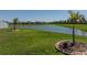 Scenic backyard view of a pond, lush green grass, and two small palm trees at 34135 White Fountain Ct, Wesley Chapel, FL 33545
