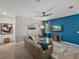 Comfortable living room featuring a blue accent wall, plush seating, stylish decor, and a contemporary ceiling fan at 34135 White Fountain Ct, Wesley Chapel, FL 33545