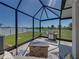 Enclosed patio featuring a grill, fire pit, seating and views of the pond at 34135 White Fountain Ct, Wesley Chapel, FL 33545