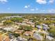 An aerial view displays a neighborhood featuring homes with pools, mature trees, and well-maintained lawns near a lake at 3957 Tarpon Pointe Cir, Palm Harbor, FL 34684
