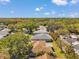 An aerial view captures neighborhood homes nestled among mature trees, with lush greenery and blue skies above at 3957 Tarpon Pointe Cir, Palm Harbor, FL 34684