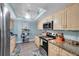 Efficient kitchen featuring light wood cabinets, granite countertops, and modern stainless-steel appliances at 3957 Tarpon Pointe Cir, Palm Harbor, FL 34684