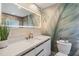 Modern bathroom with an illuminated mirror, updated fixtures, and bright leaf mural at 401 N Manhattan Ave, Tampa, FL 33609