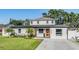 Charming two-story home featuring an orange front door, a green lawn, and mature trees providing shade at 401 N Manhattan Ave, Tampa, FL 33609