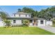 Charming two-story home featuring an orange front door, a green lawn, and mature trees providing shade at 401 N Manhattan Ave, Tampa, FL 33609