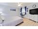 Cozy bedroom featuring light wood floors, a desk, and a dresser with TV, all bathed in natural light at 4103 Gulf Blvd # 106, St Pete Beach, FL 33706