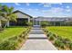Expansive backyard with steps leading up to a screen enclosed outdoor living space with views of swaying palm trees at 4204 Saltwater Blvd, Tampa, FL 33615