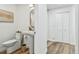 Stylish half bathroom features a pedestal sink, decorative mirror, and wood-look flooring at 4204 Saltwater Blvd, Tampa, FL 33615