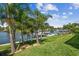 Backyard waterfront view with lush lawn, palm trees, and a private dock; an inviting outdoor oasis at 4204 Saltwater Blvd, Tampa, FL 33615