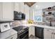 Bright kitchen features white cabinets, modern appliances, tile backsplash, window and floating wood shelves at 525 Lexington St, Dunedin, FL 34698