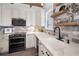 Well-lit kitchen features white cabinets, modern appliances, stylish backsplash, floating wood shelves and a sleek black faucet at 525 Lexington St, Dunedin, FL 34698