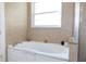 Bathroom features a large soaking tub under a window, with beige tiles and a glass-enclosed shower at 601 Gay Rd, Seffner, FL 33584