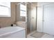 Tiled bathroom with a bathtub, glass-enclosed shower, and neutral finishes at 601 Gay Rd, Seffner, FL 33584