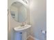 This bathroom features a round mirror above a pedestal sink and modern fixtures at 618 Wheaton Trent Pl, Tampa, FL 33619