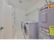 Bright laundry room featuring modern washer, dryer, storage shelves, and efficient water heater for convenience at 618 Wheaton Trent Pl, Tampa, FL 33619