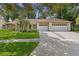 Charming single-story home featuring a three-car garage, lush lawn, and well-manicured landscaping at 6213 S Queensway Dr, Temple Terrace, FL 33617