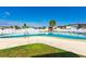 Community pool with a white fence and palm trees is ready for residents to enjoy at 7045 El Dewitt St, Zephyrhills, FL 33541