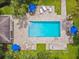 Aerial view of a pool featuring umbrellas and lounge seating surrounded by a grassy area at 7164 Twisting Pines Loop, Zephyrhills, FL 33541