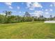 Expansive backyard featuring lush green grass, mature trees, and a serene pond view at 7164 Twisting Pines Loop, Zephyrhills, FL 33541