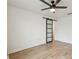 Bright bedroom with wood-look floors, a ceiling fan and modern sliding barn door at 7164 Twisting Pines Loop, Zephyrhills, FL 33541