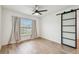 Bright bedroom with wood-look floors, a window, ceiling fan and a modern sliding barn door at 7164 Twisting Pines Loop, Zephyrhills, FL 33541