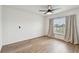 Bright bedroom with wood floors, a ceiling fan, and a large window with views of the neighborhood at 7164 Twisting Pines Loop, Zephyrhills, FL 33541