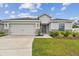 Single-story home features a two-car garage, appealing stone accents, and a well-kept front yard at 7164 Twisting Pines Loop, Zephyrhills, FL 33541