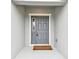 View of the home's gray front door with sidelight and welcome mat at 7164 Twisting Pines Loop, Zephyrhills, FL 33541