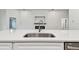 Close-up of kitchen island featuring a stainless steel sink, white countertop, and white cabinets at 7164 Twisting Pines Loop, Zephyrhills, FL 33541