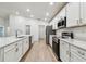 Bright, white kitchen features stainless appliances, laminate floors, and a spacious island with sink at 7164 Twisting Pines Loop, Zephyrhills, FL 33541