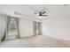 Spacious bedroom featuring plush carpeting, a ceiling fan, and natural light from two windows at 7164 Twisting Pines Loop, Zephyrhills, FL 33541
