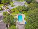 An aerial view of a community pool, surrounded by lush landscaping and featuring lounge chairs with umbrellas at 7164 Twisting Pines Loop, Zephyrhills, FL 33541