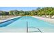 Resort-style community pool with shallow area, surrounded by lounge chairs and greenery at 7164 Twisting Pines Loop, Zephyrhills, FL 33541