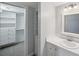 Bright bathroom featuring modern vanity, mirror and walk-in closet with shelving at 806 Linwood Ter, Lutz, FL 33549