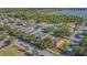 Aerial view showcases the homes, sparkling blue pool, clubhouse, and green spaces near a lake at 9205 English Oaks Ln, Riverview, FL 33578