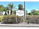 Heather Lake Condominiums sign amidst manicured hedges and palm trees at 940 Virginia St # 304, Dunedin, FL 34698