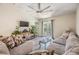 Living room features a ceiling fan, gray flooring, a cozy sectional, and sliding glass doors to the backyard at 11426 Sage Canyon Dr, Riverview, FL 33578