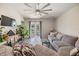 Comfortable living room with a ceiling fan, gray flooring, a cozy sectional, and sliding glass doors to the backyard at 11426 Sage Canyon Dr, Riverview, FL 33578