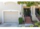 Home featuring an attached garage, brick stairs leading to the front door with decorative wreath, and manicured bushes at 1105 Venetian Harbor Ne Dr, St Petersburg, FL 33702