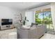 Open-concept living area featuring a plush grey sofa, modern entertainment center, and access to a screened-in porch at 1105 Venetian Harbor Ne Dr, St Petersburg, FL 33702
