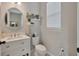 Stylish half bathroom with a white vanity, round mirror, and decorative shelves, complemented by a window with blinds at 12965 Satin Lily Dr, Riverview, FL 33579